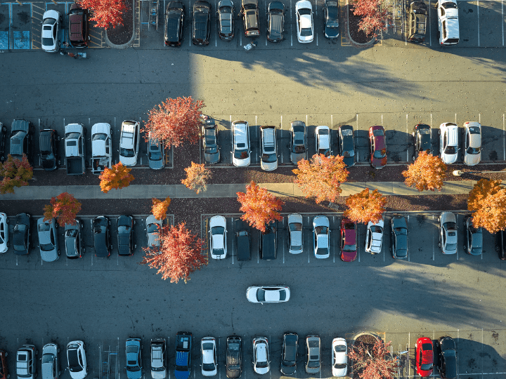 Cars parked in an outdoor lot surrounded by fall foliage.